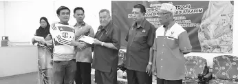  ??  ?? Speri (third, right) hands over a BR1M voucher to a recipient in Sebuyau.