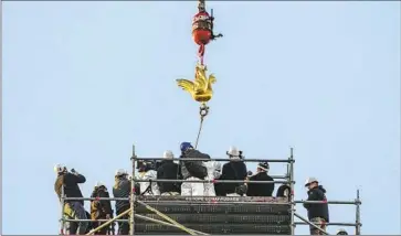  ?? THE NEW Michel Euler Associated Press ?? golden rooster is lifted by crane toward the top of Notre Dame’s rebuilt spire in Paris. The cathedral was damaged in a devastatin­g fire in April 2019. Sacred relics were placed in a hole in the rooster’s breast.