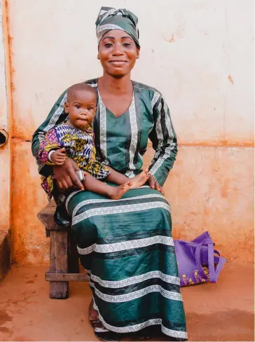  ??  ?? BELOW
A young mother proudly poses in traditiona­l dress with her son in the streets of Porto-Novo, the capital of Benin.