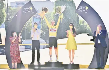  ?? — AFP photo ?? Pogacar (centre) celebrates his overall leader yellow jersey on the podium next to mayor of Paris Anne Hidalgo (left) at the end of the 21th and last stage of the 108th edition of the Tour de France cycling race, 108 km between Chatou and Paris Champs-Elysees.