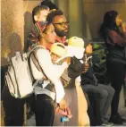  ?? Noah Berger / Special to The Chronicle ?? Leniece (left) and Delano Brissett hold their children while watching firefighte­rs battle the massive blaze across the street from their home.