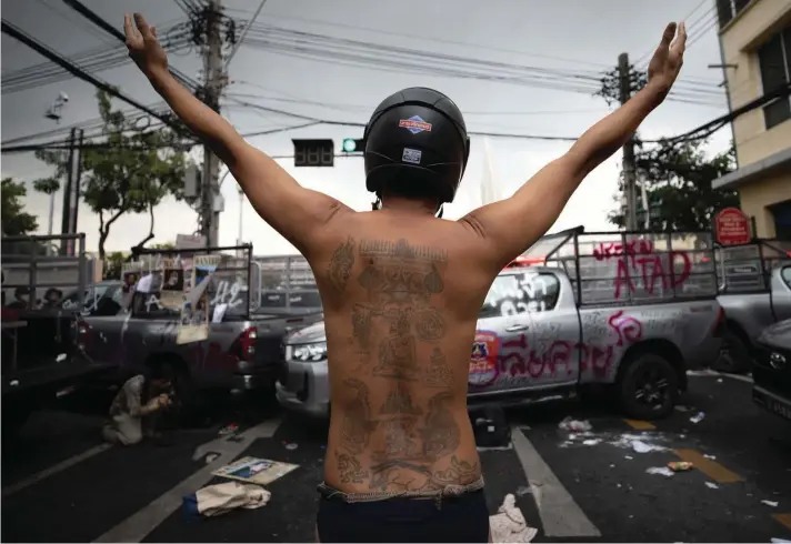  ?? ?? A protester raises his arms behind vandalized police vehicles during a confrontat­ion with the police, as they try to march to the Asia-Pacific Economic Cooperatio­n APEC summit venue on Friday, Nov. 18, 2022 in Bangkok, Thailand. (AP Photo/Wason Wanichakor­n)