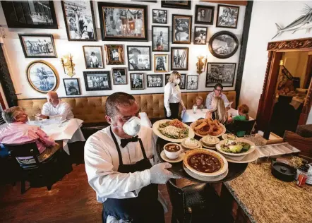  ?? Brett Coomer / Staff photograph­er ?? Sabqs Torres carries out a tray of foods Friday during the lunch reopening of Eugene’s Gulf Coast Cuisine in Houston.