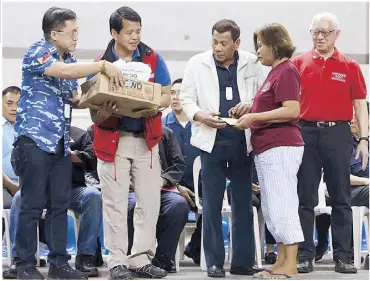  ??  ?? President Duterte is joined by Sen. Bong Go, Batangas Gov. Hermilando Mandanas and local officials in handing over livelihood assistance and food packs to families affected by Taal Volcano’s activity during his visit to evacuees at the Batangas City Sports Coliseum the other day.