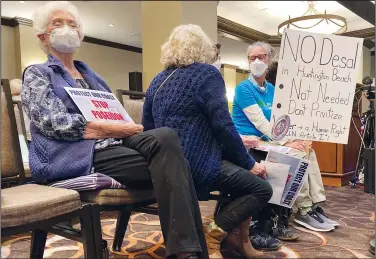  ?? (AP/Amy Taxin) ?? Community members opposed to a proposal to build a $1.4 billion desalinati­on plant in Huntington Beach sit with signs Thursday at a California Coastal Commission hearing in Costa Mesa, Calif.