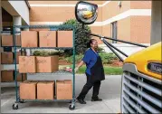  ?? CONTRIBUTE­D BY BEN GRAY ?? Gwinnett County cafeteria workers bring freshly prepared food out to waiting school buses in front of Berkmar High School so they can be delivered to students around the district last week.