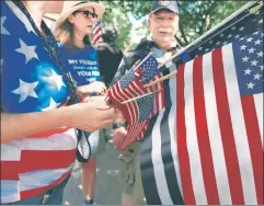  ??  ?? Colors that don’t run: Protesters in Columbus, Ohio, hand out American flags — a national symbol that an increasing­ly radicalize­d left scorns.