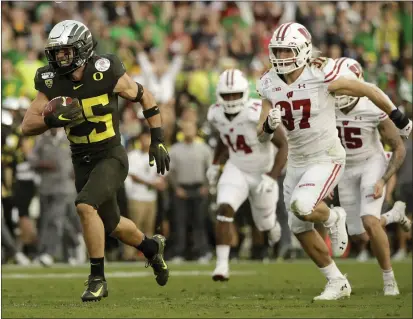  ?? MARCIO JOSE SANCHEZ — THE ASSOCIATED PRESS ?? Oregon safety Brady Breeze, left, runs for a touchdown past Wisconsin running back Garrett Groshek after a blocked punt during the second half of the Rose Bowl on Wednesday.