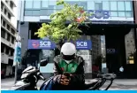  ?? ?? HO CHI MINH CITY, Vietnam: This photo taken on December 7, 2023 shows a biker using a mobile phone in front of the headquarte­rs of the Saigon Commercial Bank (SCB). — AFP