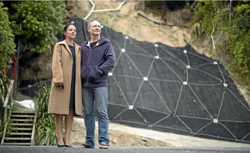  ?? ROBERT KITCHIN/STUFF ?? Jacqui Cooper and David McLaughlin stand in front of their house in Plimmerton. The house is at the top of the slip site, and because of the slip, there is no longer any access.