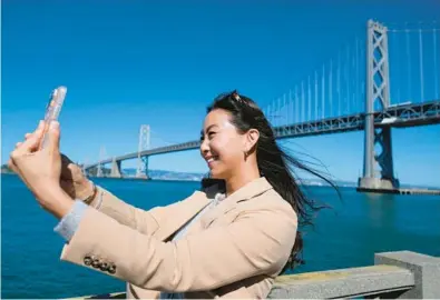  ?? ERIC RISBERG/AP ?? Content creator Cynthia Huang Wang works Monday near the San Francisco-Oakland Bay Bridge in San Francisco.