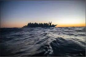  ?? (AP/Bruno Thevenin) ?? Migrants and refugees from African nations wait for assistance in February aboard a crowded wooden boat in the Mediterran­ean as aid workers of the Spanish NGO Open Arms approach.