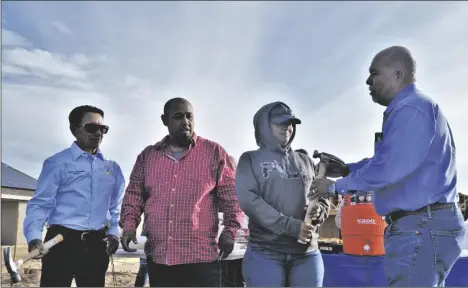  ?? FILE PHOTO ?? TONY REYES, EXECUTIVE DIRECTOR of the Comite de Bien Estar, presents a symbolic hammer to a family building a home in San Luis, Ariz., through a self-help housing program administer­ed by the Comite.