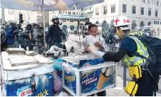  ??  ?? A first aid volunteer helps an ice-cream vendor pack up his stall after police fired tear gas during a march.