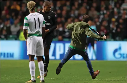  ??  ?? A supporter runs onto the pitch at Celtic Park during the club’s 5-0 defeat to Paris Saint-Germain in last night’s Champions League match