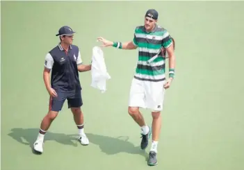  ??  ?? ► Isner le pasa la toalla a un pasapelota­s, imagen que grafica lo alto que es.