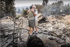  ?? HECTOR AMEZCUA / SACRAMENTO BEE ?? Dan Spraggins (right), 79, of Lake Redding Estates, gets a hug from a friend at the burned-out remains of his home on Friday. “This was a beautiful home,” Spraggins said.