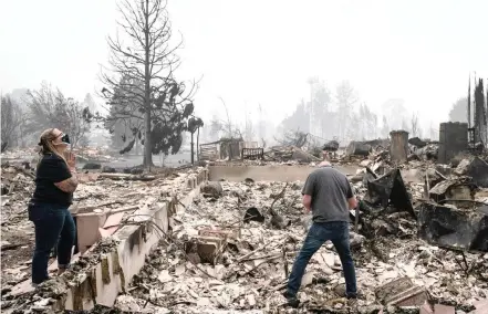  ?? | Reuters ?? A COUPLE look at the remains of their home which was gutted by a wild fire in Talent, Oregon, at the weekend.