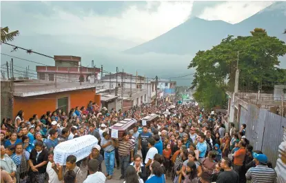  ??  ?? Familiares y amigos llevan los ataúdes de siete víctimas de la erupción en el pueblo de Alotenango.