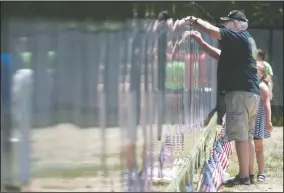  ?? BEA AHBECK/NEWS-SENTINEL ?? Vietnam veteran Gary Henry, with granddaugh­ter Payton Henry, 8, traces the name of his friend, John Brandborg, at the Vietnam Moving Wall at the Weber Point Events Center in Stockton on Friday.