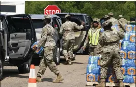  ?? PHOTOS BY STEVE HELBER — THE ASSOCIATED PRESS ?? Members of the Mississipp­i National Guard distribute water and supplies to residents in Jackson, Miss., on Friday.