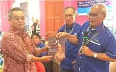  ??  ?? Jabu (right) presents a copy of his autobiogra­phy to longhouse chieftain Segan Jubin, as Salang (centre) looks on.