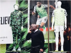  ?? AP ?? In this June 5, 2018 photo a man stands in front of a Nigerian national football team jersey is on display at a shop in London.