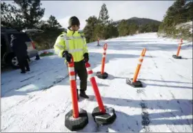  ?? DAVID ZALUBOWSKI — THE ASSOCIATED PRESS ?? Park ranger Kevin Sturmer drags pylons up Trail Ridge Road to block access after an overnight snow was left unplowed in Rocky Mountain National Park Saturday in Estes Park, Colo. Roads were unplowed in the park because a partial federal shutdown has been put in motion because of gridlock in Congress over funding for President Donald Trump’s Mexican border wall.