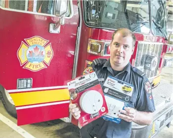  ?? BOB TYMCZYSZYN/POSTMEDIA NETWORK ?? Ben Trendle, a captain with the Niagara Falls Fire Department, holds up a smoke and CO2 for the Wake Up campaign. Throughout the month of May, firefighte­rs will go door-to-door on Mondays, Tuesdays, Wednesdays and Thursdays to check if homes are...