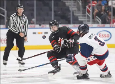  ?? The Canadian Press ?? Team Canada defenceman Kaedan Korczak, of the WHL’s Kelowna Rockets, chips the puck past the United States’ Mike Koster (3) during first-period action in their Hlinka Gretzky Cup semifinal on Friday night in Edmonton. Canada won 6-5 in overtime.