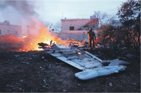  ?? AFP ?? A rebel fighter stands over a downed Russian Sukhoi-25 fighter jet in Idlib province, Syria, in February