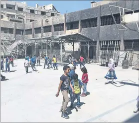  ?? THE ASSOCIATED PRESS ?? Syrian students play in the courtyard of a school whose walls are still charred and pockmarked with bullets from recent fighting in the town of Douma, in the Ghouta region.