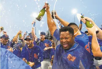  ?? James Durbin / Midland (Texas) Reporter-Telegram 2014 ?? Webster Garrison, then DoubleA Midland’s hitting coach, hoists a Champagne bottle to celebrate a 50 win over Tulsa in the final game of the 2014 Texas League championsh­ip series.