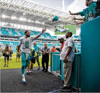  ?? ALLEN EYESTONE / THE PALM BEACH POST ?? Dolphins quarterbac­k Matt Moore (8) tosses his hat to fans as he exits the field after coming off the bench to direct a 31-28 comeback victory over the Jets at Hard Rock Stadium. Moore passed for 188 yards and two touchdowns.