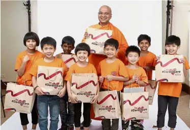  ??  ?? All smiles: Dhammarata­na with the children of Ti-Ratana posing with the DaretoCare bags.