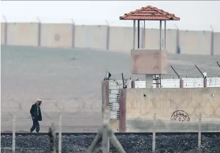  ?? EMRAH GUREL/THE ASSOCIATED PRESS ?? A man walks in Islamic State-controlled Tal Abyad, Syria, by a Turkish border station. The Canadian government is not commenting on Turkish media reports that a man alleged to have smuggled three British girls into Syria may have Canadian intelligen­ce...