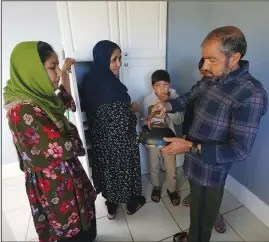  ??  ?? Abdul (right), who worked as a mechanic before he left Kabul, Afghanista­n, with his family about a month ago, shows his family a donated tea kettle Thursday in Seattle.