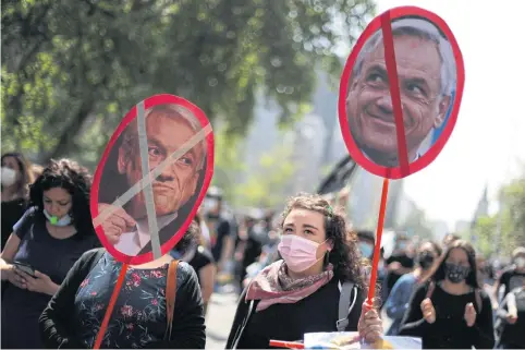  ?? PHOTOS BY REUTERS ?? Demonstrat­ors hold banners with images of Chilean President Sebastian Pinera calling for Mr Pinera’s resignatio­n on Wednesday.