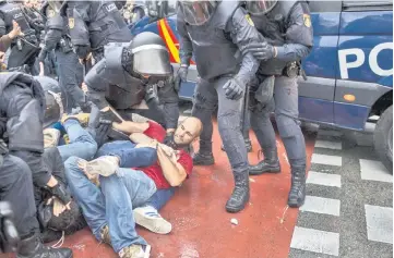  ??  ?? People clash with Spanish police officers outside the Ramon Llull polling station. — AFP photo