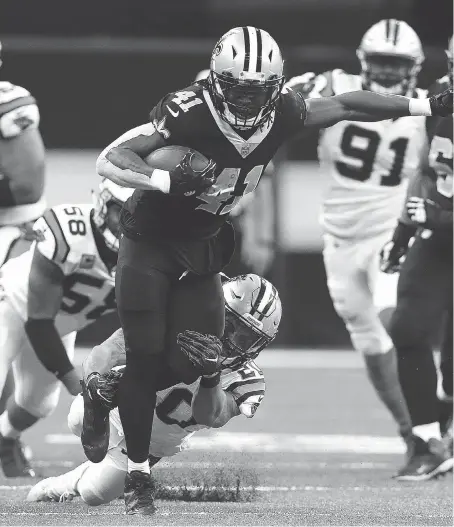  ?? SEAN GARDNER/GETTY IMAGES ?? New Orleans Saints running back Alvin Kamara gets tackled from behind by Carolina Panthers safety Kurt Coleman in the second half on Sunday in New Orleans. Kamara scored two touchdowns in Sunday’s win, and now has TDs in six straight games.