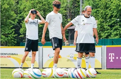  ?? Foto: Christian Charisius, dpa ?? Matthias Ginter (li.) und Thomas Müller versetzen sich mit Augenbinde­n in die Lage von Blindenfuß­ballern. Rechts: Peter Gössmann, Bundestrai­ner der deutschen Blinden fußball Nationalma­nnschaft.