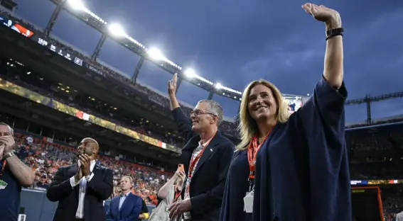  ?? Aaron Ontiveroz, The Denver Post ?? Carrie Walton Penner and Greg Penner of the Walton Penner group wave on the sidelines during the first quarter of Saturday night’s preseason game against the Dallas Cowboys at Empower Field at Mile High.
