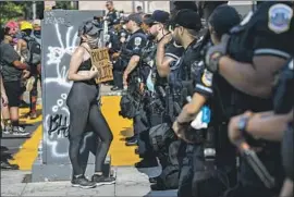  ?? Jacquelyn Martin Associated Press ?? A PROTESTER confronts police on 16th Street this week. Anti-police-brutality activists have criticized Bowser over her proposal to increase police funding.