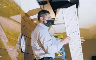  ?? GRANT HINDSLEY/THE NEW YORK TIMES ?? Building engineer Armando Garcia installs air filters this month in an office building in Seattle.