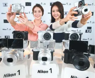  ?? Yonhap ?? Models promote Nikon’s new mirrorless camera, the Nikon 1 J5, during a media event at the Gran Seoul Building i n Jongno, central Seoul, Thursday. The Japanese camera-maker said the new device is capable of recording 4K-class video and executing 20...