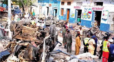  ??  ?? Somali security forces and civilians walk among damages at the scene of a blast on Sunday, a day after two car bombs exploded in Mogadishu. (AFP)