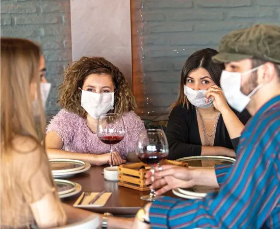  ??  ?? COVERING UP: A group of diners wearing face masks. Left: A thermomete­r being used to check a person’s temperatur­e