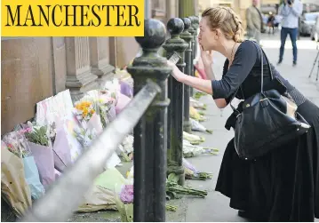  ?? JEFF J MITCHELL / GETTY IMAGES ?? A woman reflects by the flowers left in Manchester’s St. Ann Square on Tuesday, a day after a suicide bombing at a pop concert that killed 22 people in the worst terror incident on British soil since the London bombings of 2005.