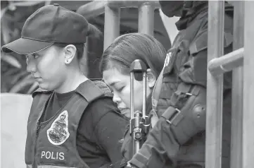  ??  ?? File photo shows Siti Aisyah (centre) being escorted with a heavy police presence after a court appearance with Doan Thi Huong at the magistrate­s’ court in Sepang. — AFP photo