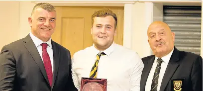  ??  ?? Centre Alex Hughes is awarded the Best 1st XV Back award by former Wales internatio­nal Rowland Phillips, left, and club president Tom Pullman, right